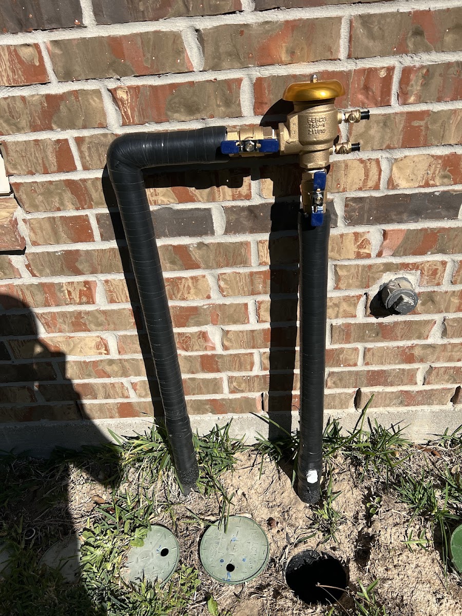 Clean backflow preventer assembly mounted against a brick wall