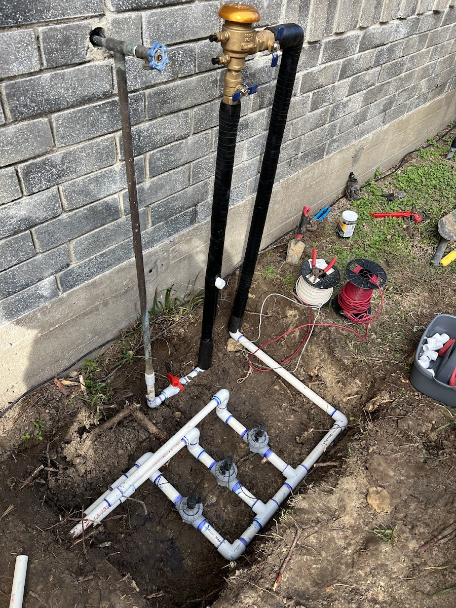 PVC manifold being installed in a trench with tools nearby