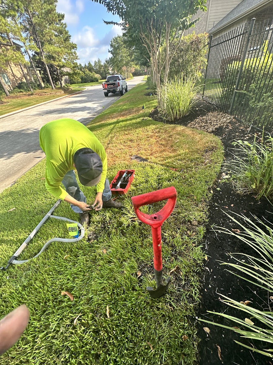 Technician working on a sprinkler head in a lush lawn